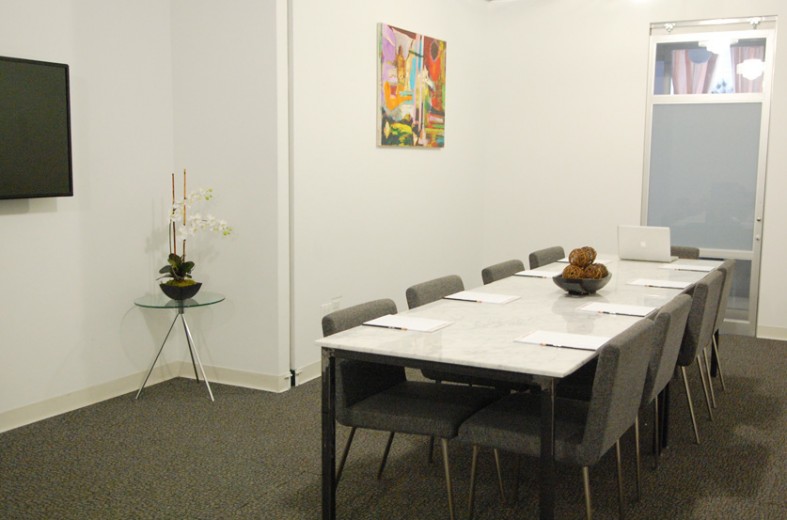 The School of hardstocks room in white color, painting, flower base, long table with folders and laptop.